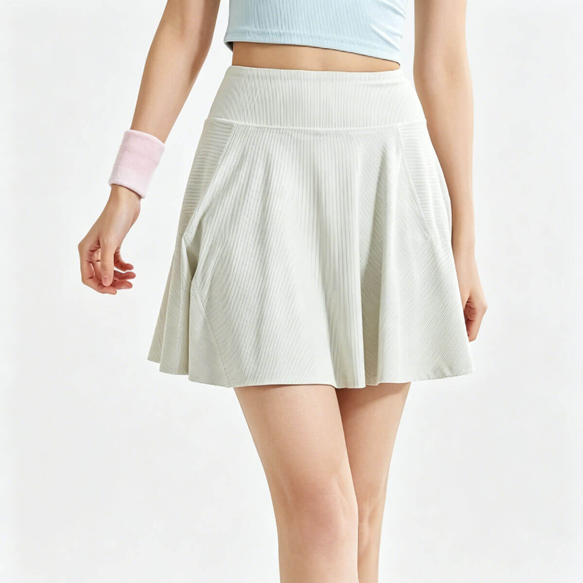 Front view of high-waisted ribbed tennis skirt in apricot, featuring a pleated A-line silhouette for athletic wear.