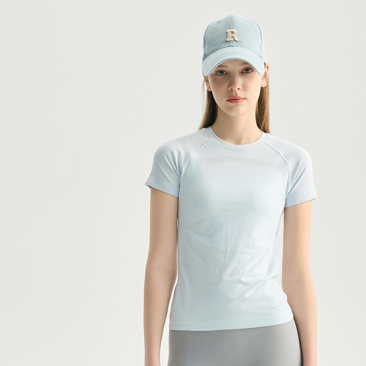 Front view of a woman wearing an ice blue yoga workout t-shirt made of soft, high-stretch fabric.