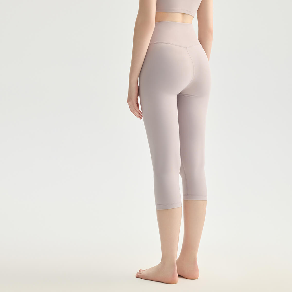 Rear view of a woman wearing lavender purple crop leggings designed for yoga, Pilates, and gym.
