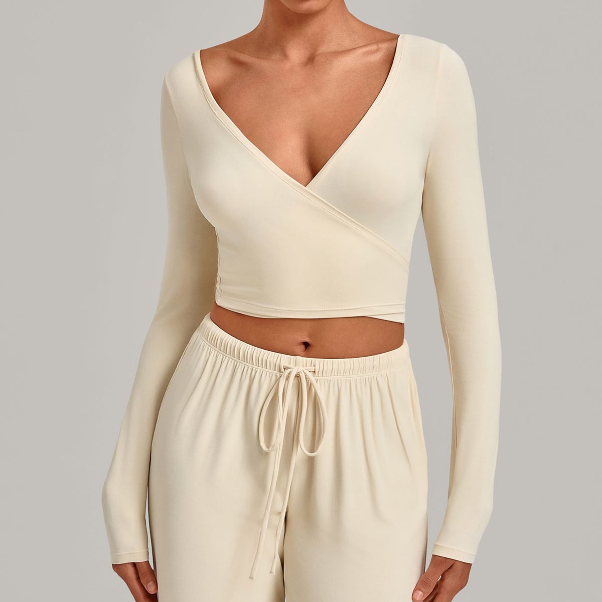 Front view of an ivory cream long-sleeve ballet wrap crop top.