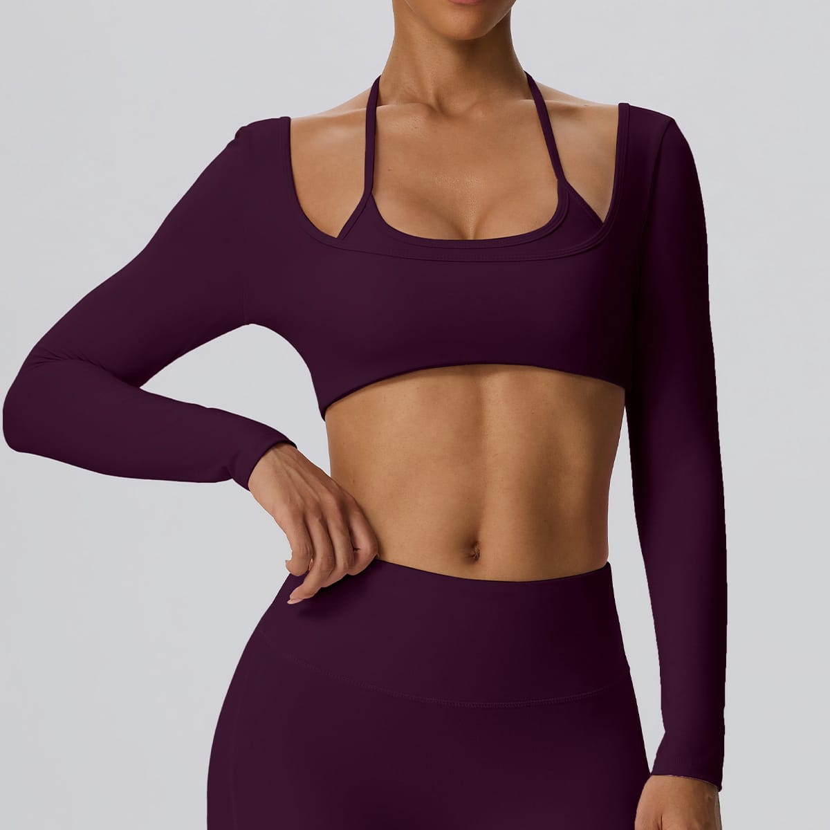 Side angle of a model wearing a deep plum long sleeve cutout workout top.