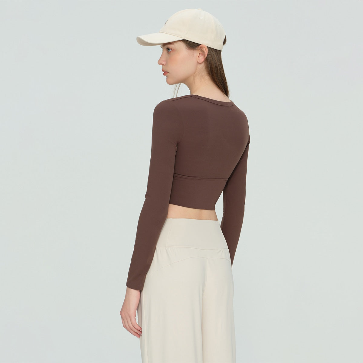Back view of a chocolate brown fitted long-sleeve athletic crop shirt.