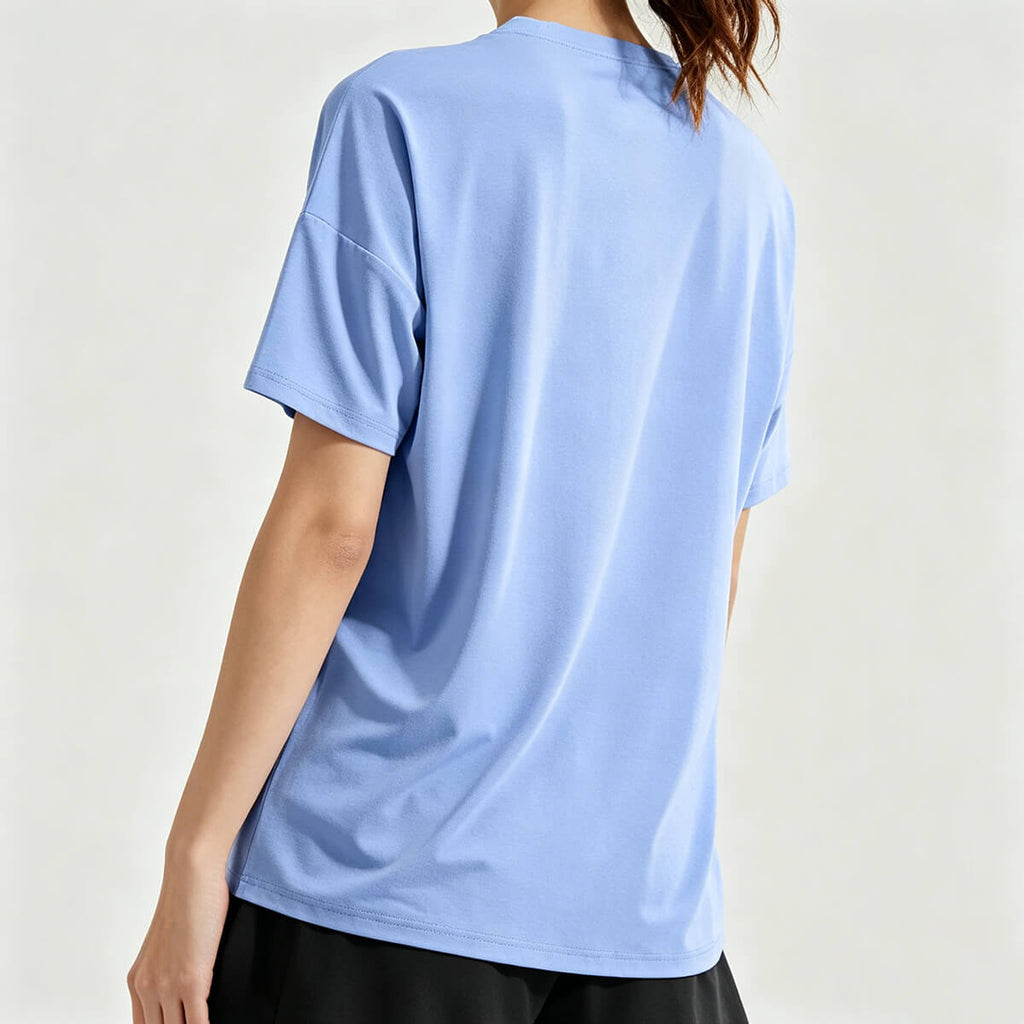 Back view of the women's loose gym tee in light blue, highlighting the relaxed fit and drop shoulder design for maximum comfort.