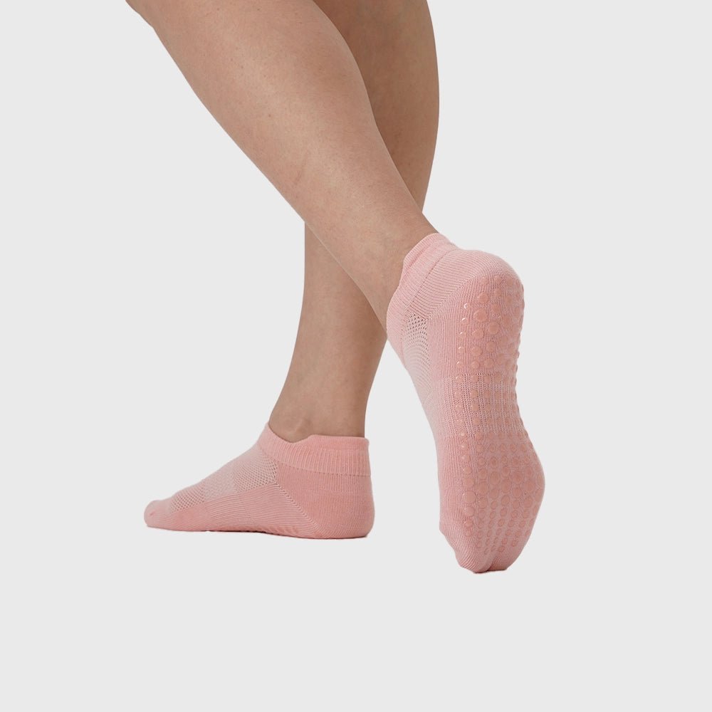 Sole view showing full silicone traction grip dots on women's pink ankle pilates socks with custom logo, athletic apparel manufacturer.