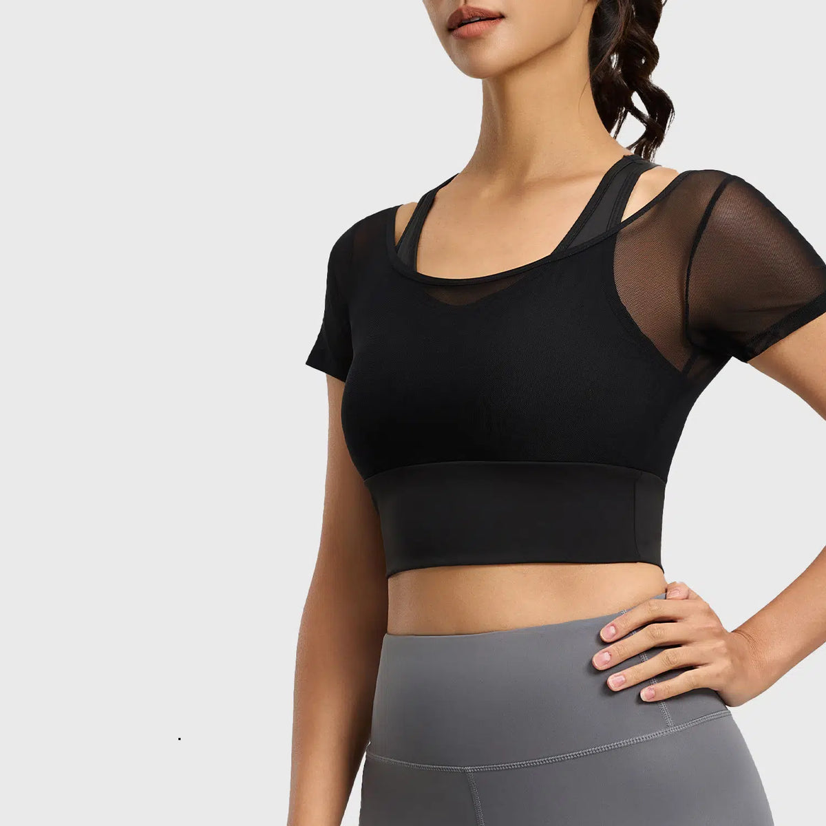 Women's sheer mesh short sleeve sports bra crop top with non-removable pads in black with custom logo, direct clothing manufacturer - front view.
