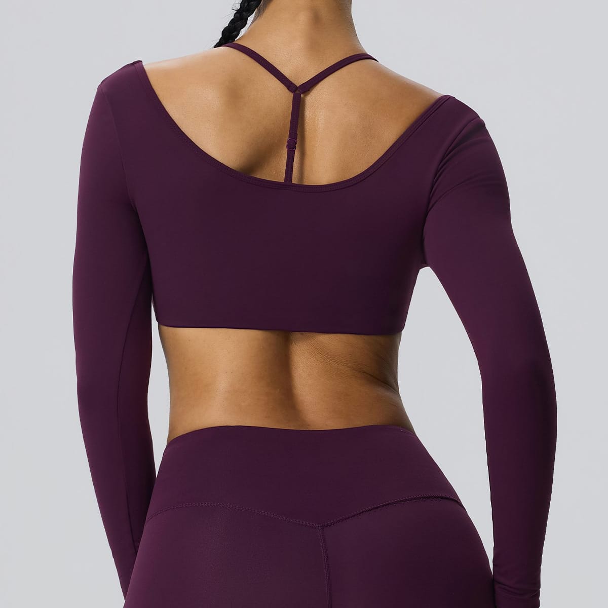 Back view of a deep plum shrug sports bra showing the open-back strap design.