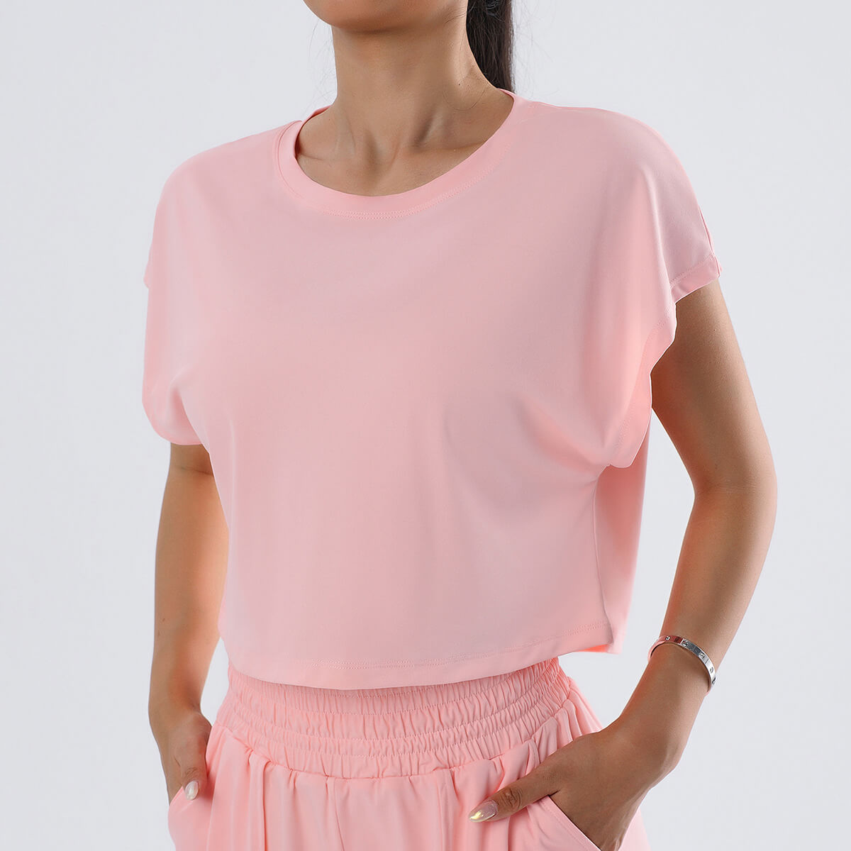 Front view of a woman wearing a loose-fit blush pink cropped workout t-shirt.