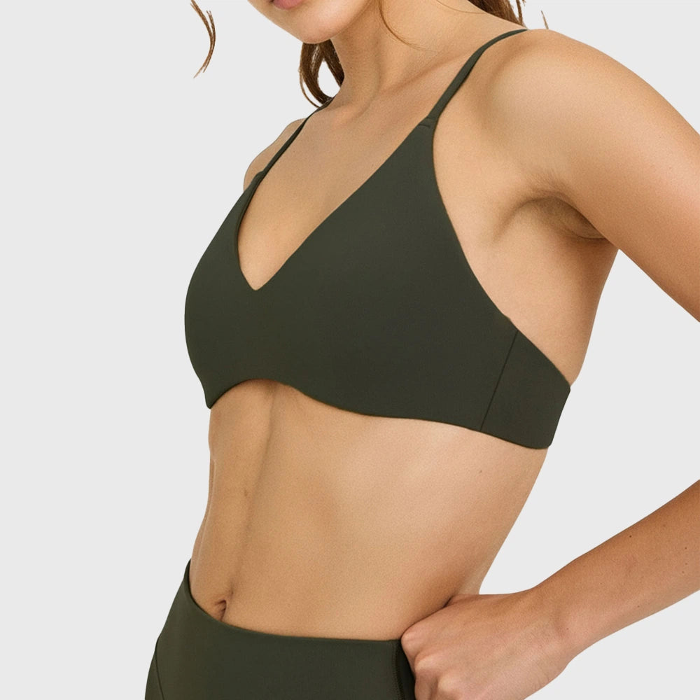 Side profile of women's plunge v-neck yoga sports bra in dark olive green with custom logo, produced by activewear manufacturer.