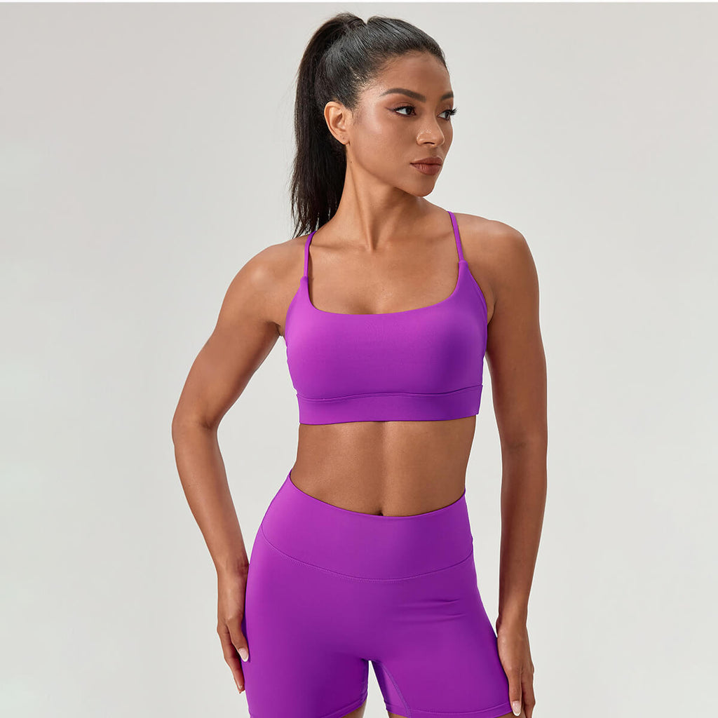 Full front view of a woman in a vibrant purple two-piece yoga set, including a scoop-neck bra and compression biker shorts.