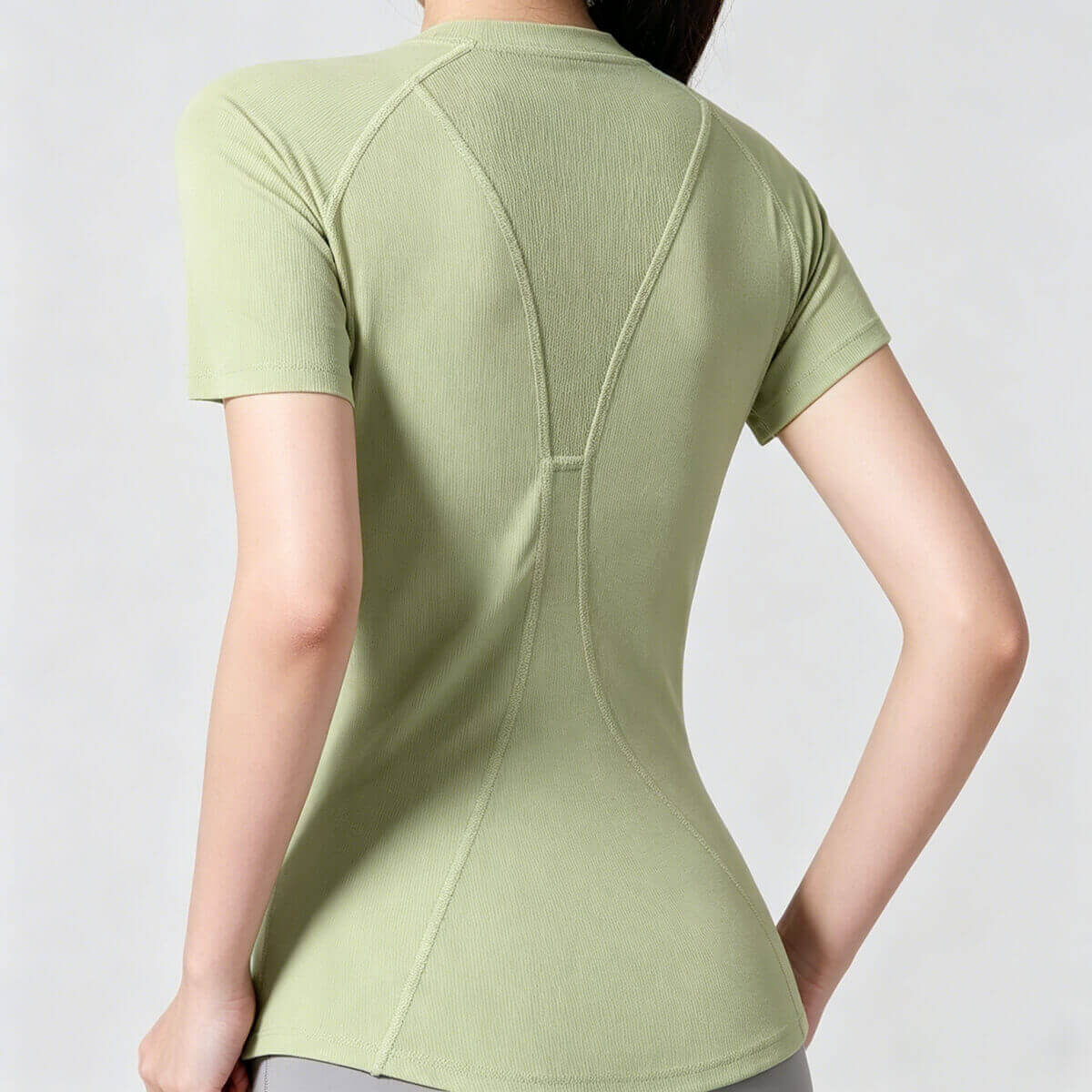 Rear view of a sage green quick-dry yoga shirt for women, highlighting the ergonomic seams and cooling mesh panel detail