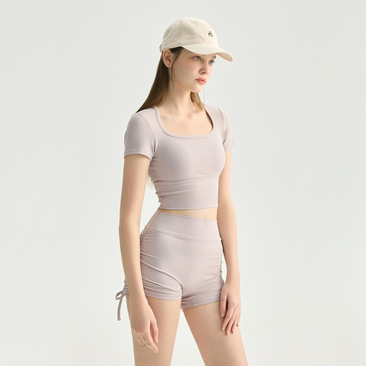 Model wearing dusty mauve high-waisted side-drawstring workout shorts set.