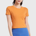 Women's short sleeve padded athletic running crop top in orange with custom logo, fitness clothing manufacturer - front view.
