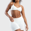Women's halter neck seamless yoga sports bra in white with custom logo, sportswear manufacturer - front view.