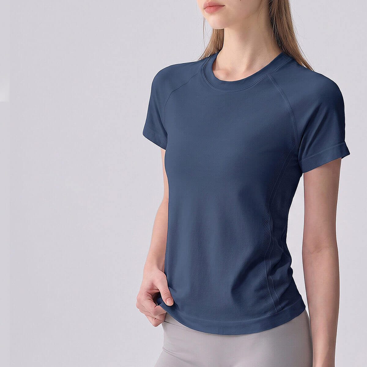 Woman wearing a slate blue short sleeve seamless athletic workout shirt.