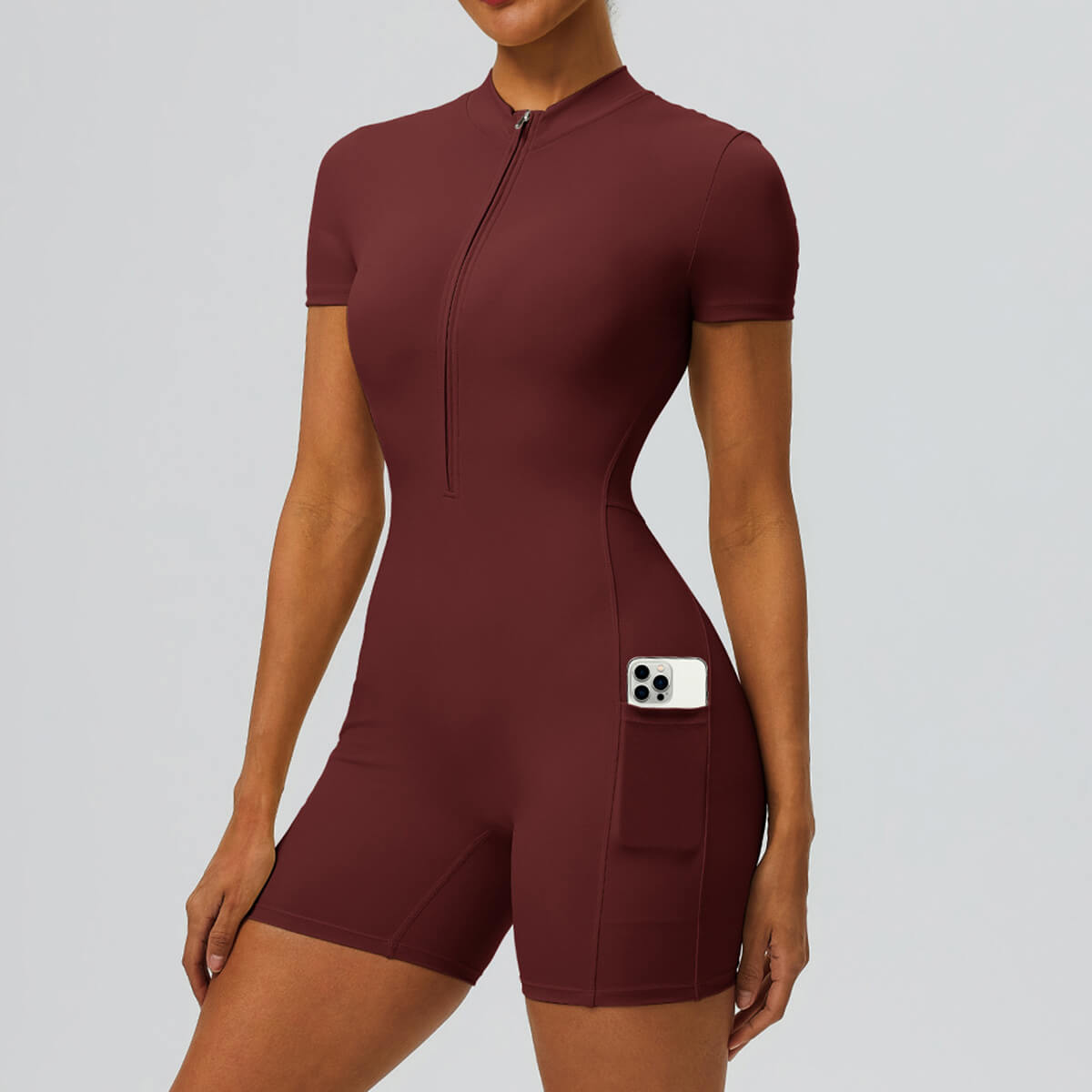 Front view of a burgundy red short-sleeve athletic romper with a side pocket.