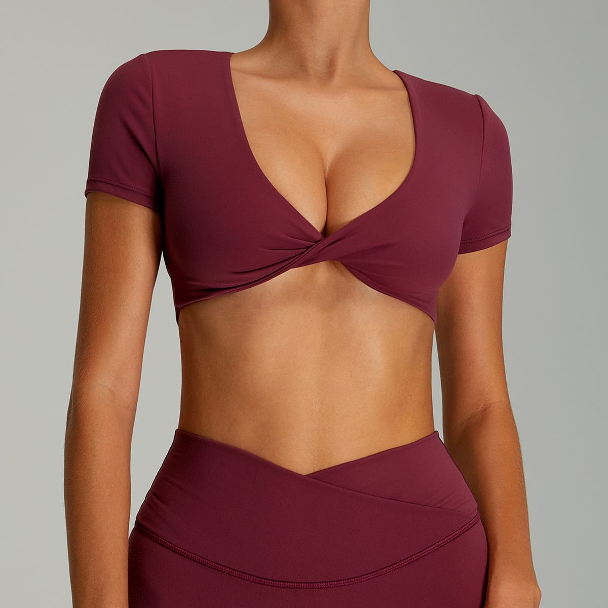 Woman wearing a deep wine red twist-front short-sleeve workout top.
