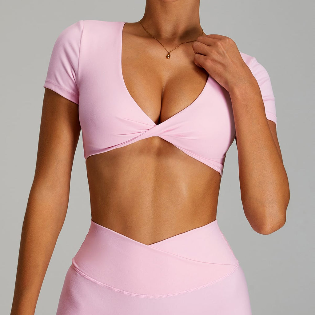 Front view of a pastel pink short-sleeve twist-front workout crop top.