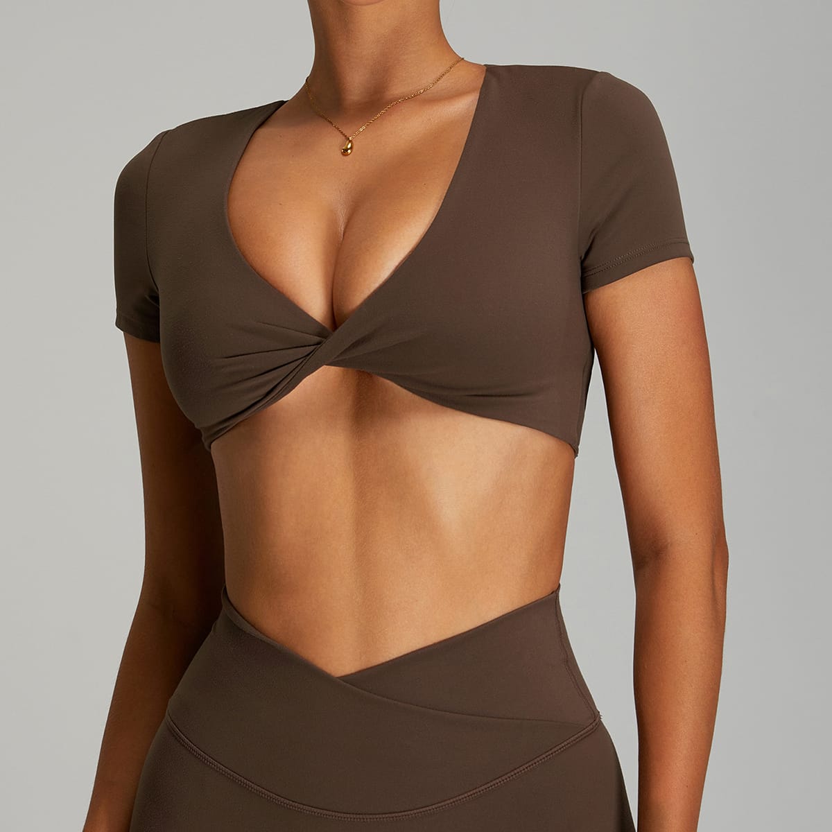 Front view of an espresso brown short-sleeve twist athletic crop bra.