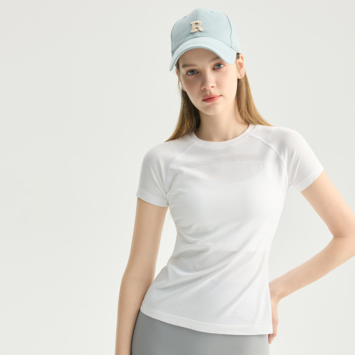 Front view of a woman wearing a white slim-fit athletic tee with breathable textured detailing.