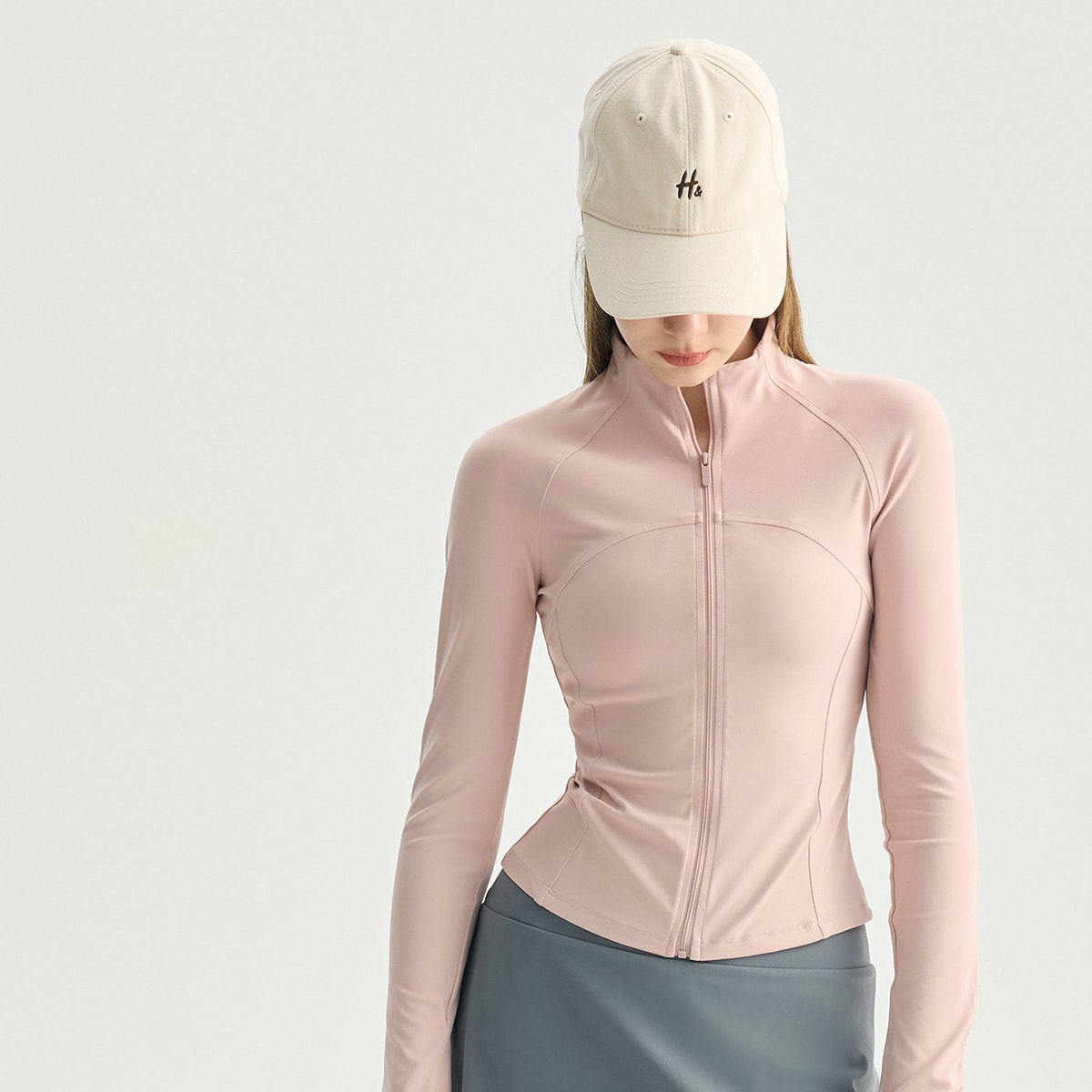 Woman wearing a blush pink slim-fit full-zip athletic running jacket.