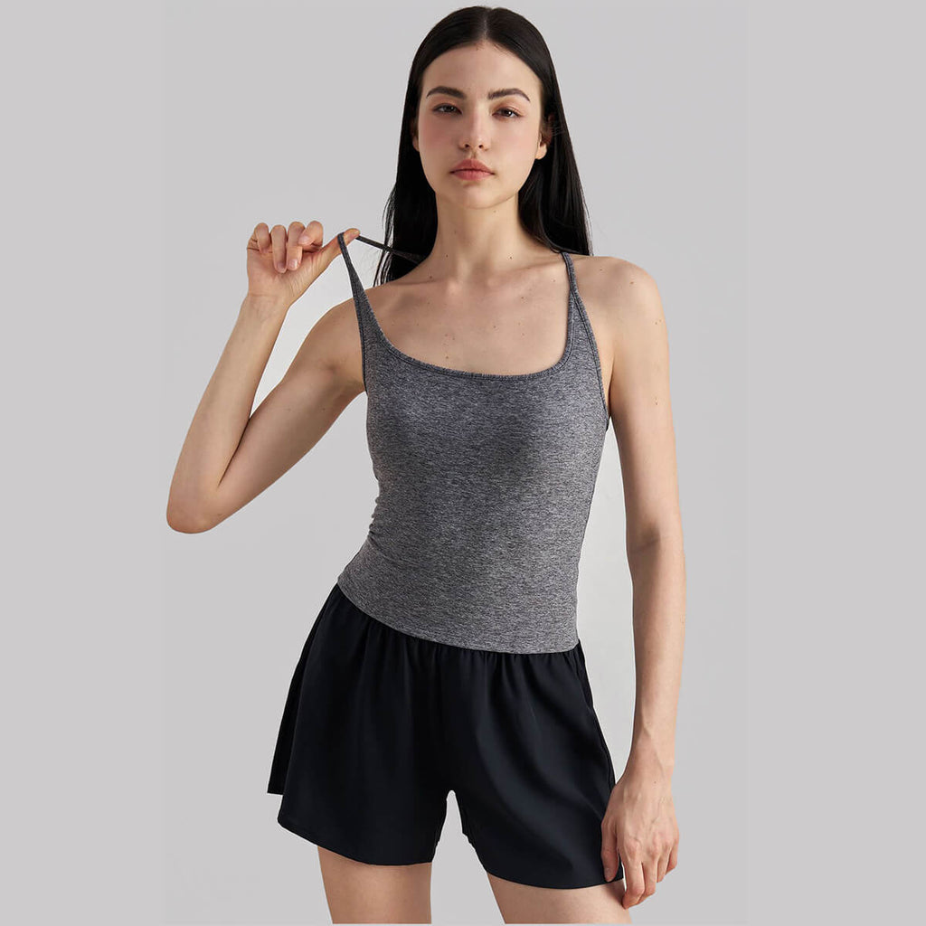 Close-up of a woman adjusting the thin shoulder strap of a gray square-neck workout tank top.
