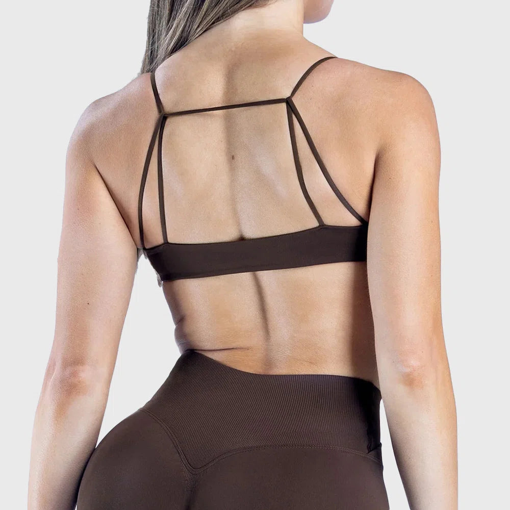 Strappy open back and geometric strap design on dark brown sports bra with custom logo, manufactured by fitness clothing manufacturer.