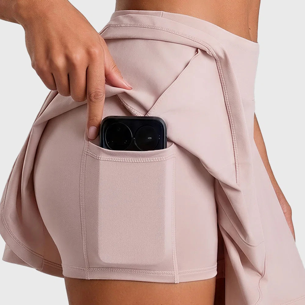 Built-in shorts with phone pocket feature on pink tennis skort with custom logo, manufactured by athletic wear manufacturer.