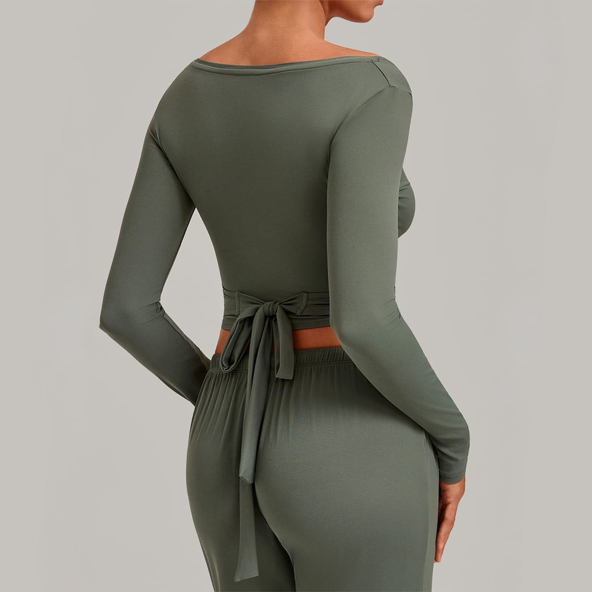Side back view of a sage green ballet wrap top showing tie-back bow detail.