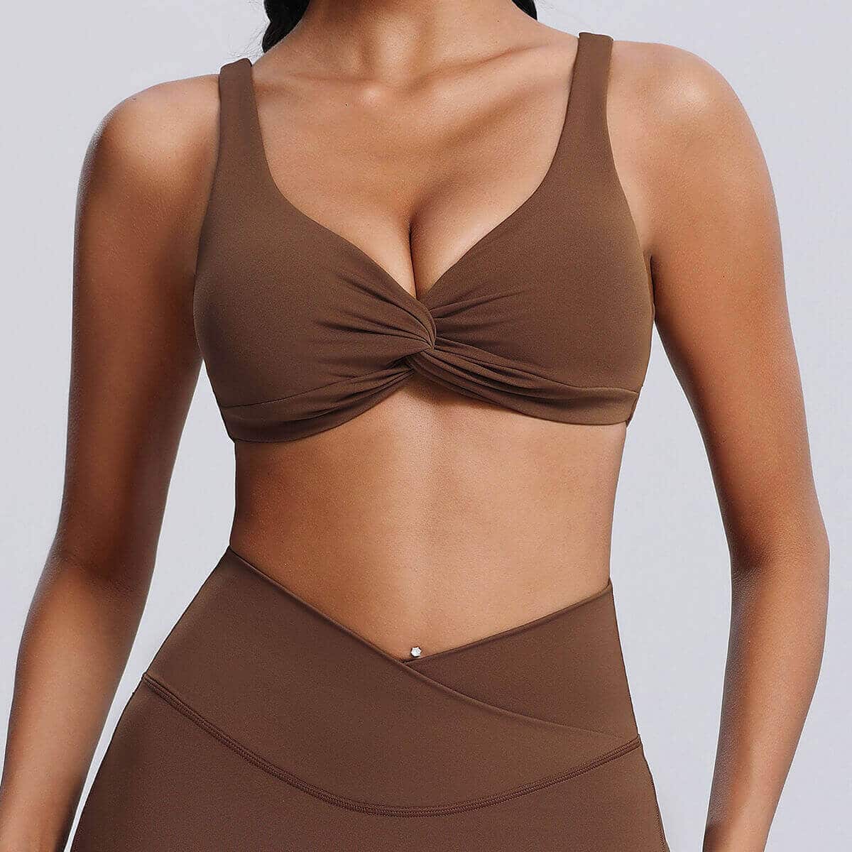 Woman wearing a chocolate brown twist-front yoga sports bra.