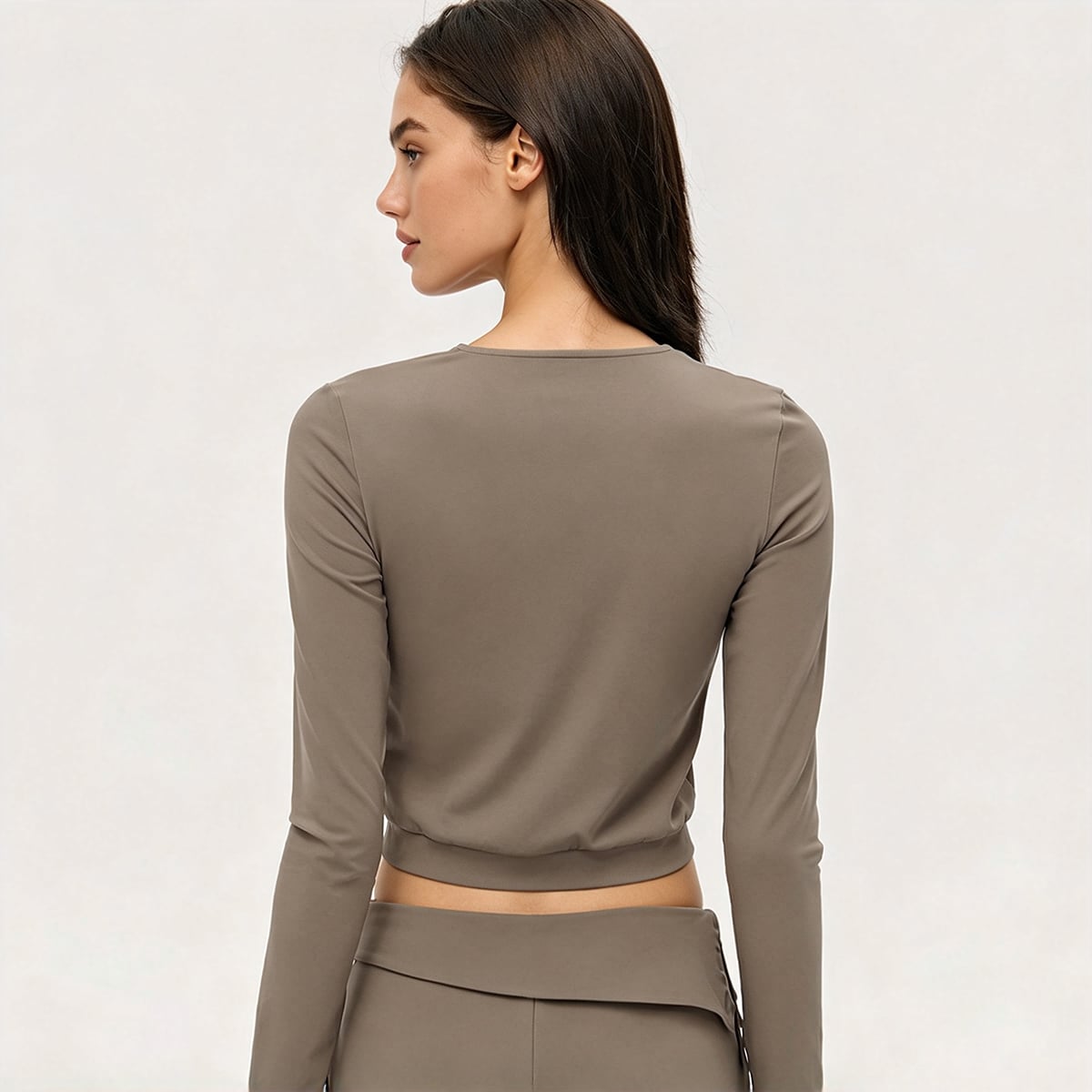 Back view of a taupe cropped zip-up athletic jacket with elastic hem.