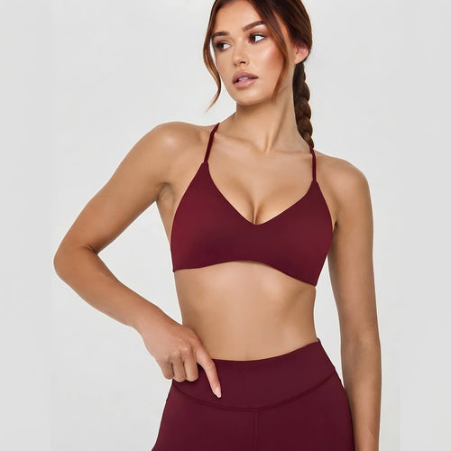 Front view of a woman wearing a burgundy V-neck sports bralette with delicate thin straps, paired with matching leggings for a coordinated look.