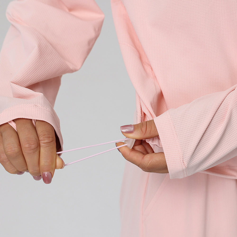Close-up detail of adjustable cinch drawstring hem and thumbholes on women's pink sweatshirt with custom logo, fitness clothing manufacturer.
