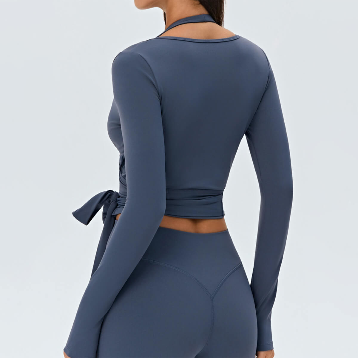 Rear view of the slate blue wrap-around gym top showing the contoured waist and elegant V-cut back.