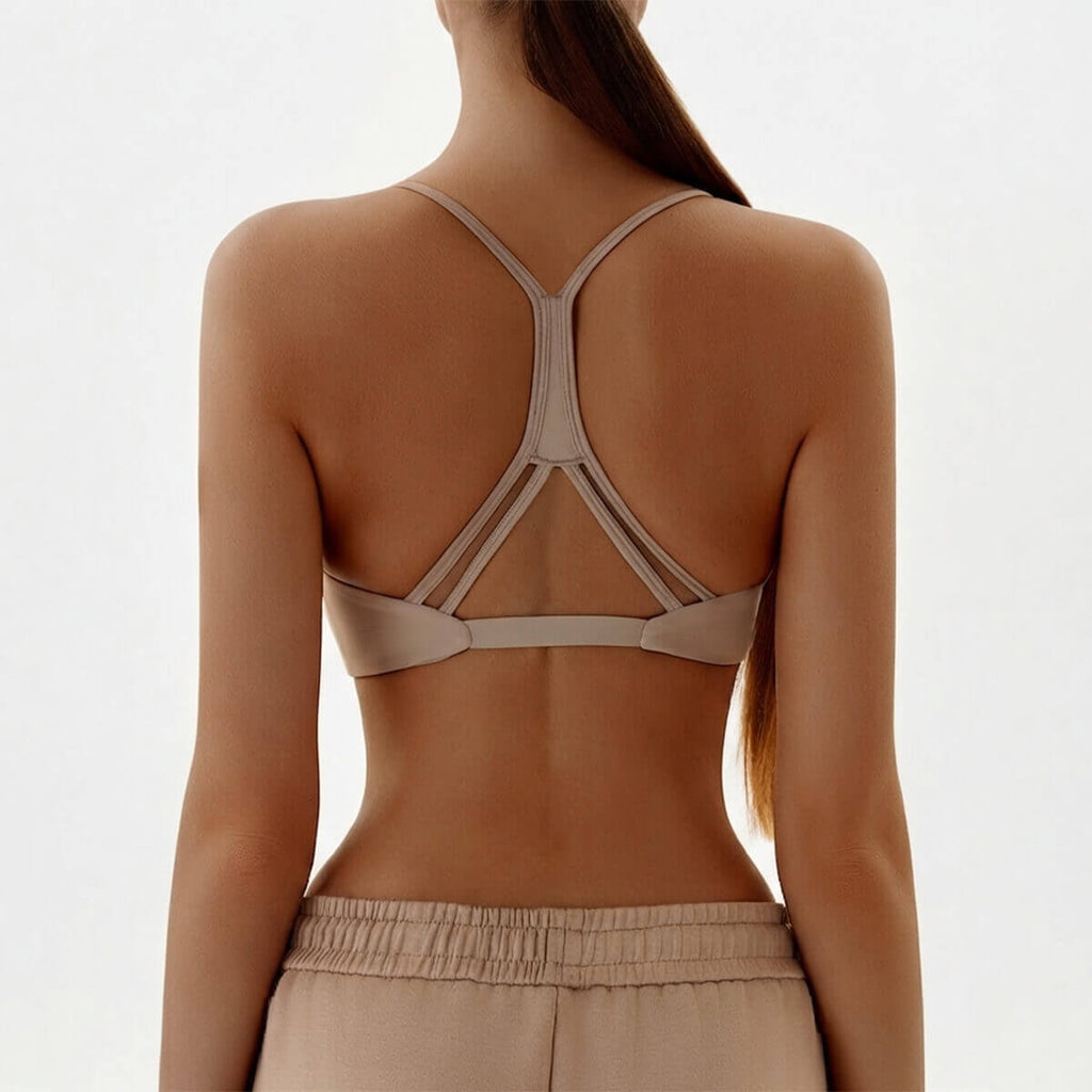 Back view of a nude sports bra featuring a minimalist Y-back strap design with a unique geometric triangle cutout.
